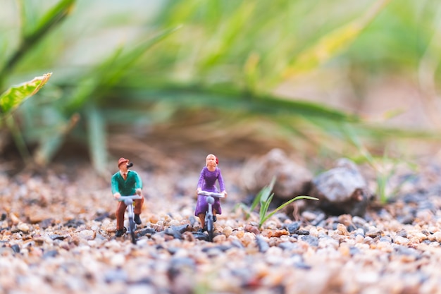  Miniature people: Travellers riding a bicycle  on The sand