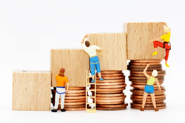 Photo miniature people with coins stack and wooden box.