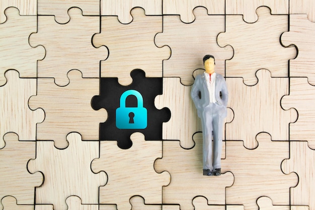 Foto persone in miniatura con l'icona della chiave sul foro del puzzle in legno. il concetto di password o identità, futuro