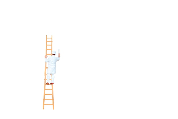 Photo miniature people with ladder holding brush in front of a white wall background