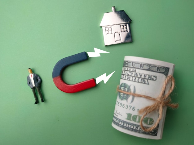 Miniature people with magnet attract house and banknote The concept of buying a home