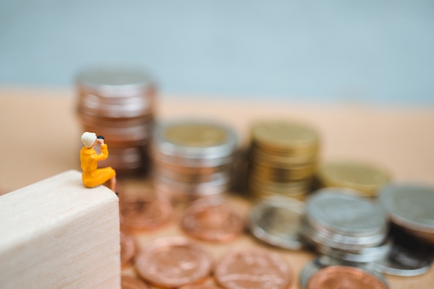 Miniature people, woman looking to stack coins using as business and financial concept