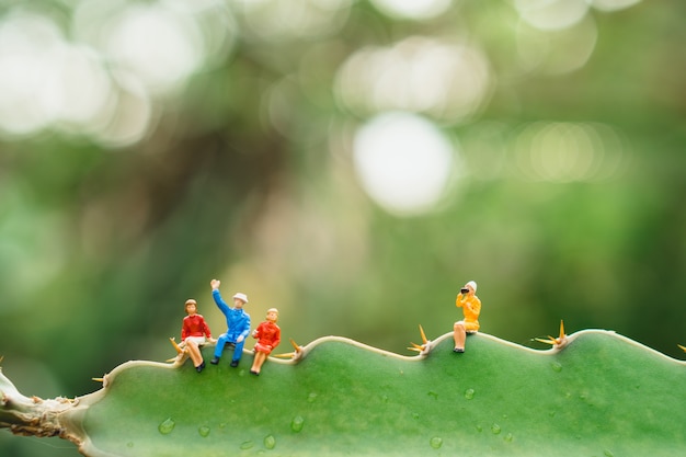 Photo miniature people woman sitting on green nature sugar palm leaf