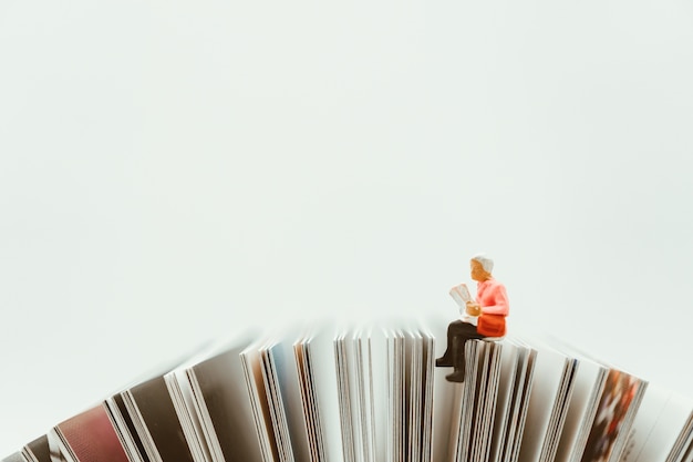 Photo miniature people,woman sitting on paper using as education and holiday