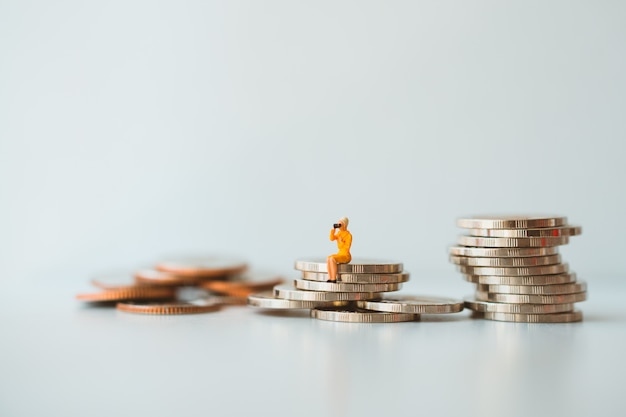 Miniature people, woman sitting on stack coins using as business and financial concept