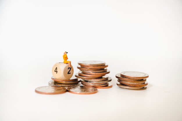 Photo miniature people, woman sitting on stack coins