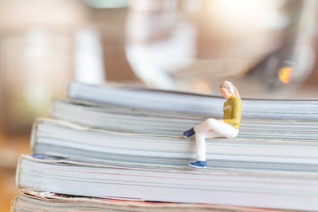 miniature people woman wearing headphones and listening to music on smartphone