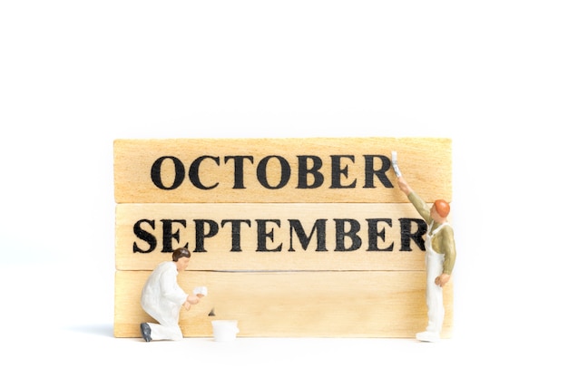 Miniature people ,Worker painting October on wooden block on white background.