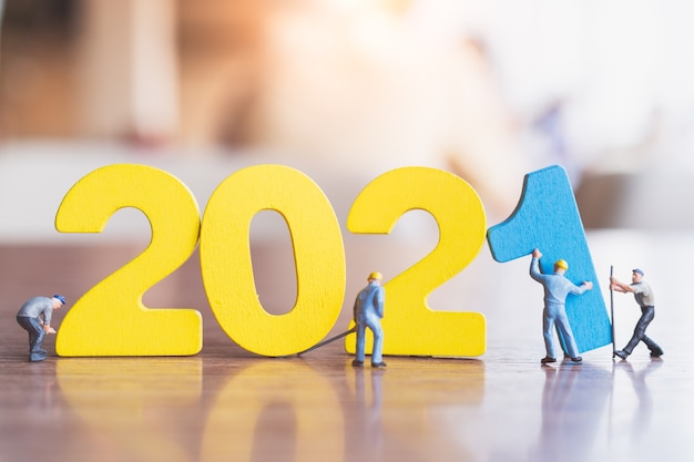 Miniature people : Worker team build wooden number 2021  , Happy new year concept