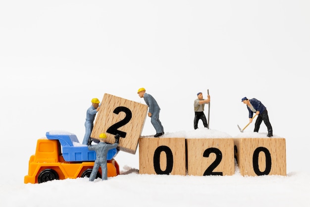 ミニチュアの人々、労働者チームは木製のブロック番号2020を作成します