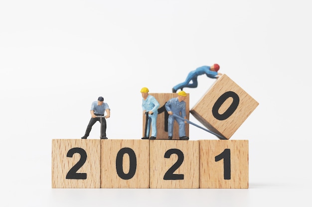 Persone in miniatura: la squadra di lavoratori crea il blocco di legno numero 2021, concetto di felice anno nuovo