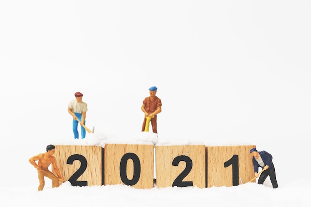 Миниатюрные люди: команда рабочих создает деревянный блок номер 2021, концепция с новым годом