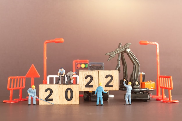 Miniature people : Worker team create wooden block number 2022 , Happy new year concept