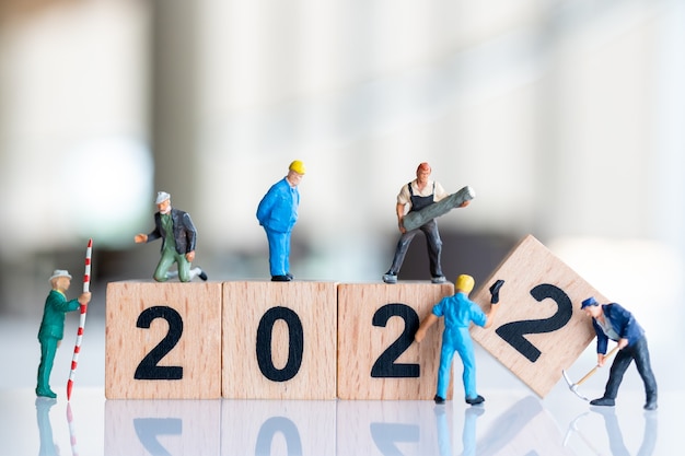 Miniature people : Worker team create wooden block number 2022 , Happy new year concept