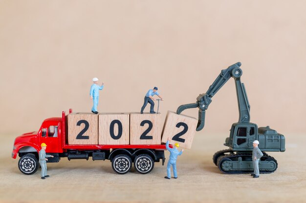 Persone in miniatura: il team di lavoratori crea il blocco di legno numero 2022, concetto di felice anno nuovo