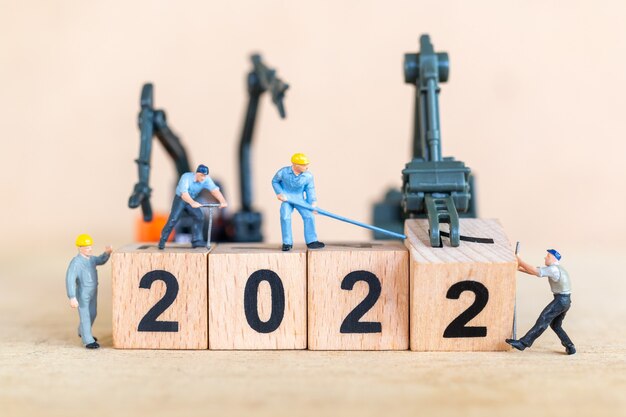 ミニチュアの人々：労働者チームは木製のブロック番号2022、新年あけましておめでとうございますのコンセプトを作成します