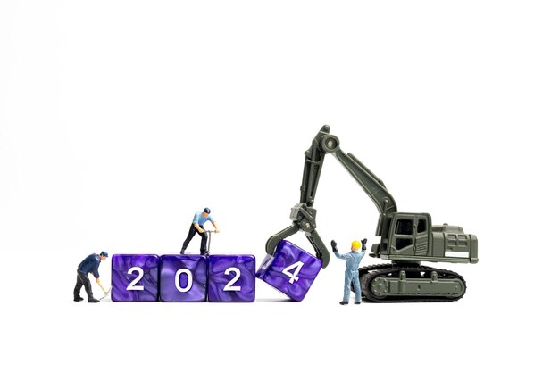 Miniature people Worker team flips a block with the number 2024