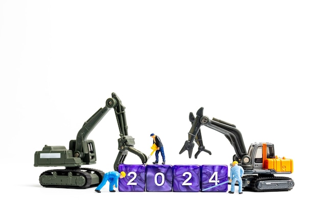 Photo miniature people worker team flips a block with the number 2024