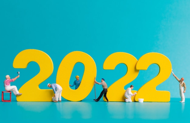 Squadra di lavoratori in miniatura che dipinge numero 2022, concetto di felice anno nuovo