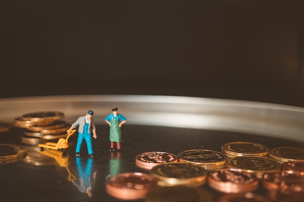 Photo miniature people, workers lifting stack coins