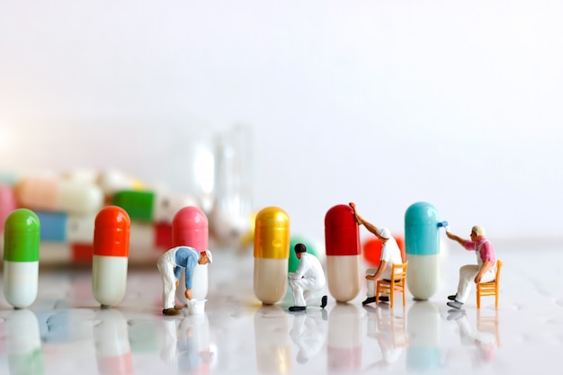 Miniature people: Workers  team brush painting Medicinal capsules. Healthcare and Medical concept.