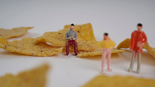 Foto persone in miniatura che lavorano o siedono intorno al cibo tortilla chips mais chip