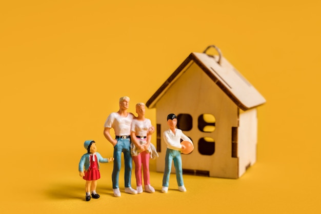 Miniature people on a yellow background a young family and real estate