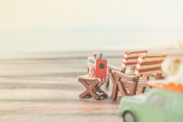 Miniature radio on a table and beach chair with sea background.