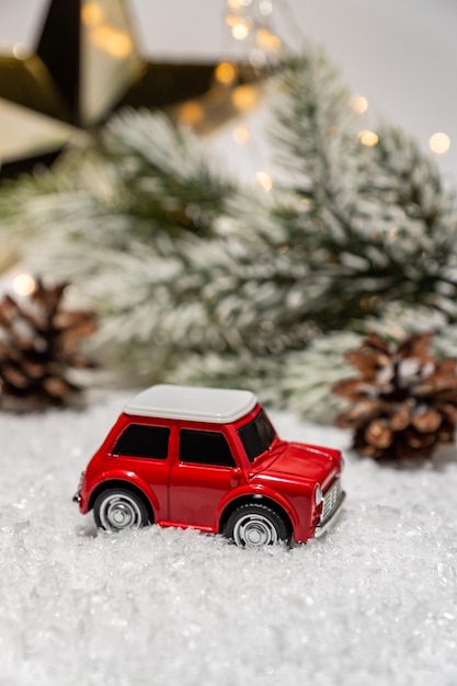 가문비나무가 있는 소형 빨간 장난감 자동차 겨울 방학 배경 크리스마스 컨셉 휴일 배달 크리스마스 장식 및 보케 조명