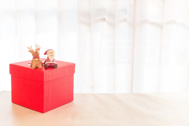 Photo miniature santa claus and reindeer decoration with packing red parcels box.