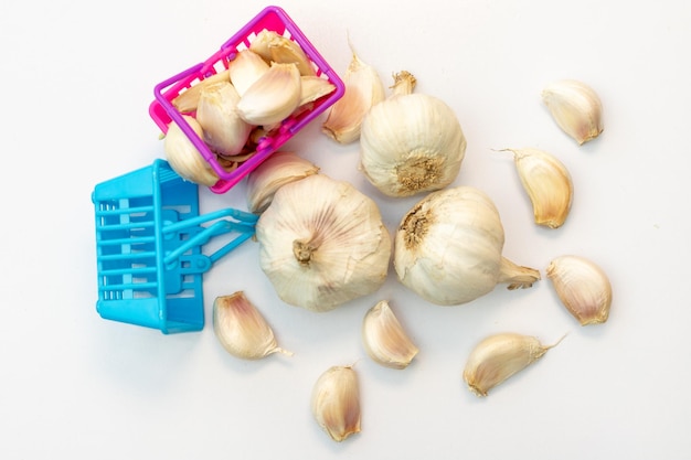 Miniature shopping basket with garlic bulbs and cloves isolated on a white background grocery shopping concept