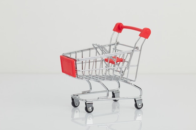 Miniature shopping cart and basket on white