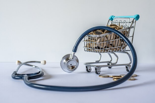 Miniature shopping cart full of coins and a stethoscope