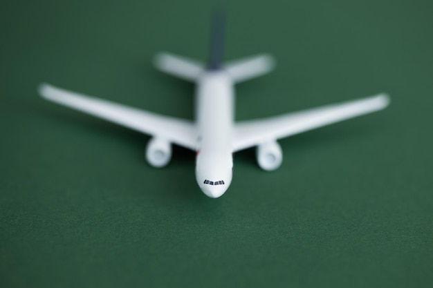 Miniature toy airplane on green background summer holiday air\
travel by plane concept