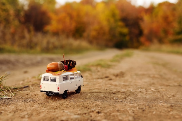 Miniature toy car minivan carries on the roof yellow leaves