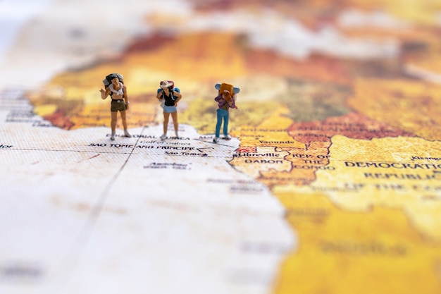 Foto viaggiatore in miniatura con uno zaino in piedi sulla mappa del mondo. concetto di viaggio.