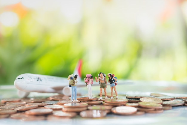 Foto miniatura di viaggiatori sono in piedi su una pila di monete