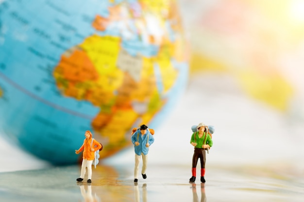 Miniature travelers and backpack on map and globe, Concept of travel around the world and adventure.
