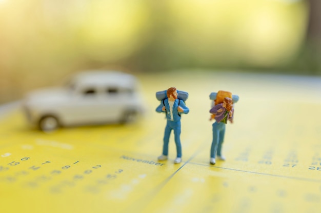Foto viaggiatori in miniatura con uno zaino in piedi sul calendario, viaggi e concetto di vacanza.