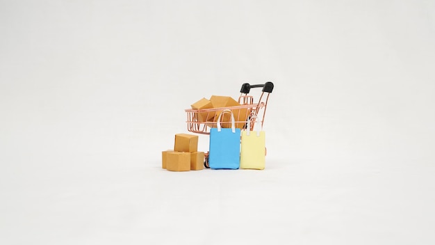 Carrello in miniatura pieno di scatole colorate e mini borse isolate su sfondo bianco