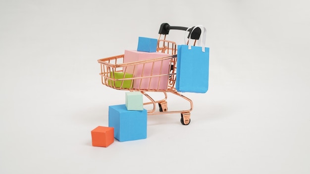 Miniature trolley filled with colorful boxes and mini bags isolated on white background