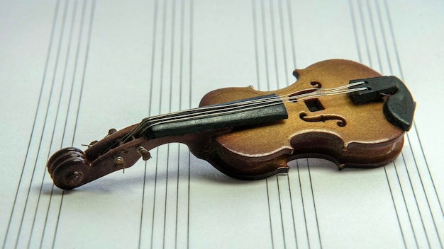 A miniature violin lies on top of the sheet music