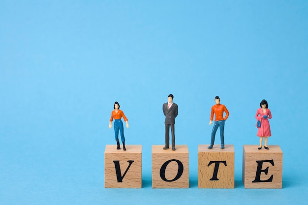 Foto elettori in miniatura su cubi di legno con la parola voto