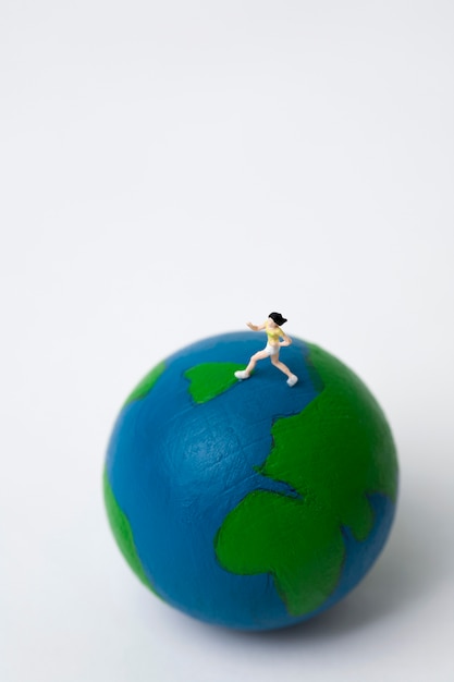 miniature woman running on globe on white