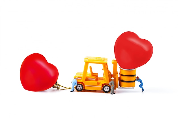 Lavoratore in miniatura e piccolo carrello elevatore con la palla del cuore, giorno di s. valentino.