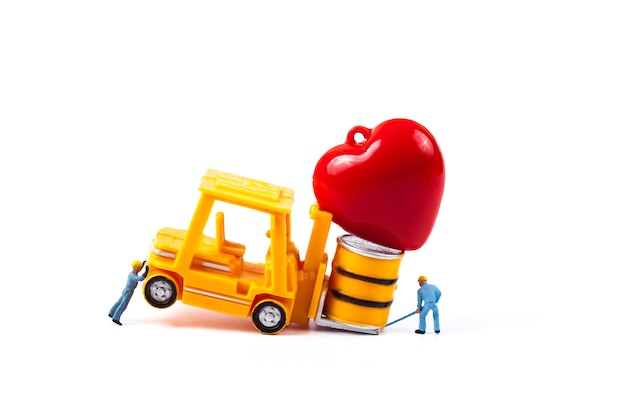 Operaio in miniatura e piccolo carrello elevatore con segno del cuore di amore