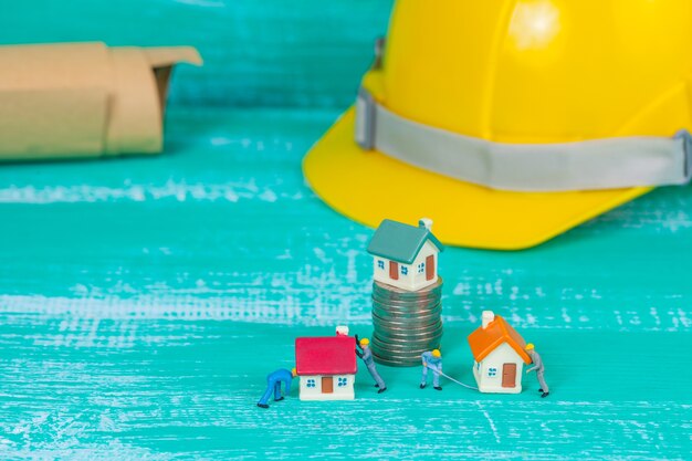 Photo miniature worker and small house on coin stack