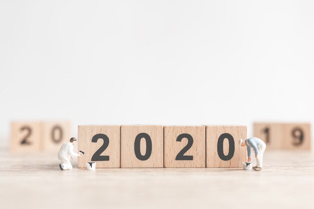 Foto il team di lavoratori in miniatura ha dipinto il numero 2020 e rimuove il numero 2019