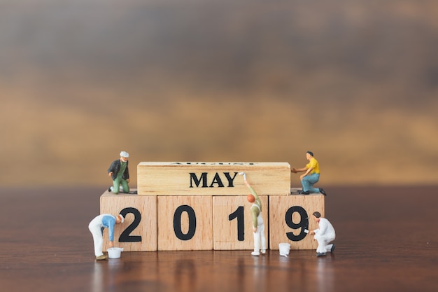 Photo miniature worker team painting  on wooden block