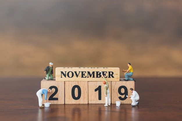 Miniature worker team painting  on wooden block 